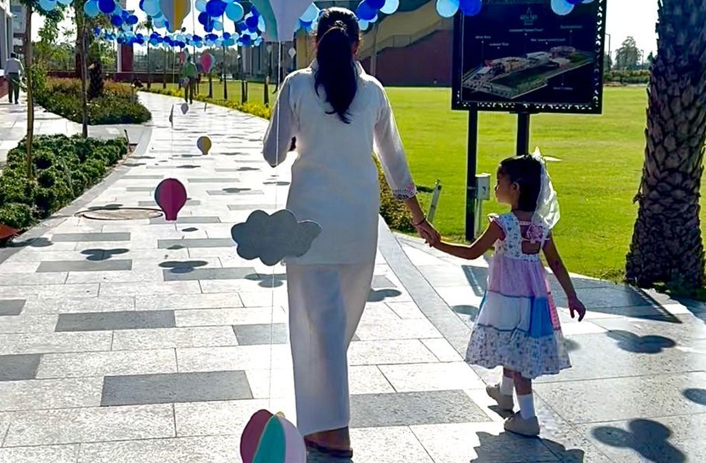 A mother and daughter are walking down a path decorated by balloons