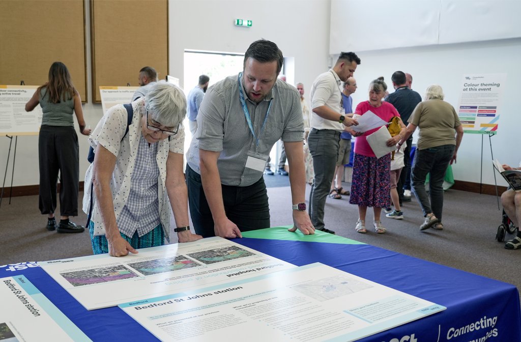 A member of staff speaks with an attendee of the Bedford EWR over a table full of plans and maps at the non statutory consultation event at King’s House on Ampthill Road on Friday, 23 May. Image: EWR Co.