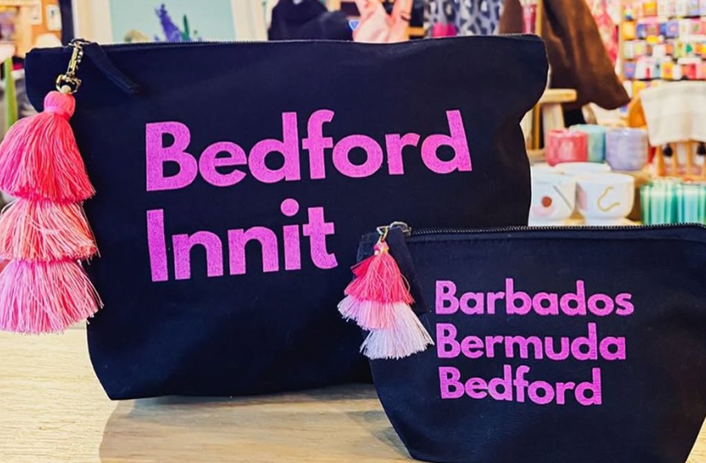 Two black make-up pouches with screenprinted wording. One says Bedford Innit and the other says Barbados, Bermuda, Bedford in hot pink.
