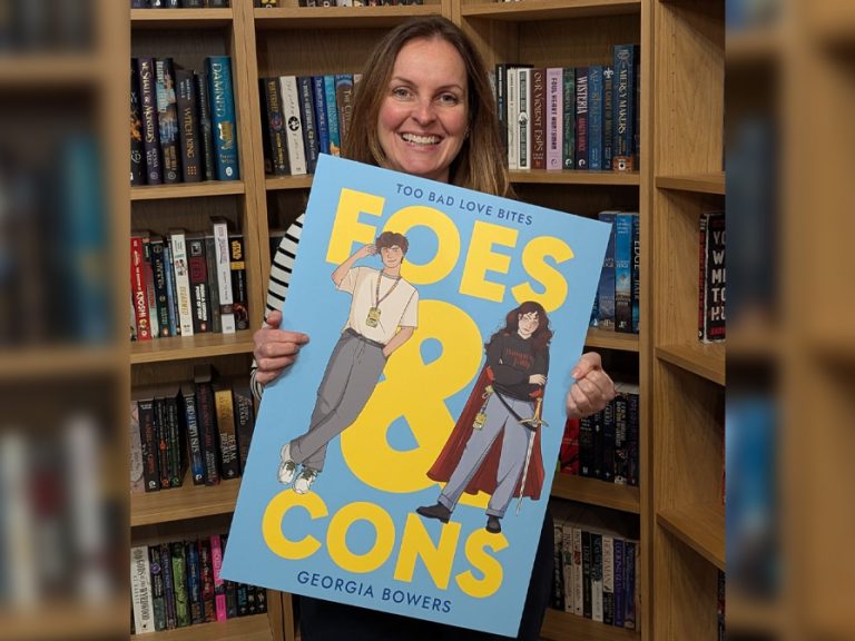 Georgia Bowers, Bedford Borough librarian and first-time author holding a mock-up of the cover of her debut novel Foes & Cons. Image Bedford Borough Council