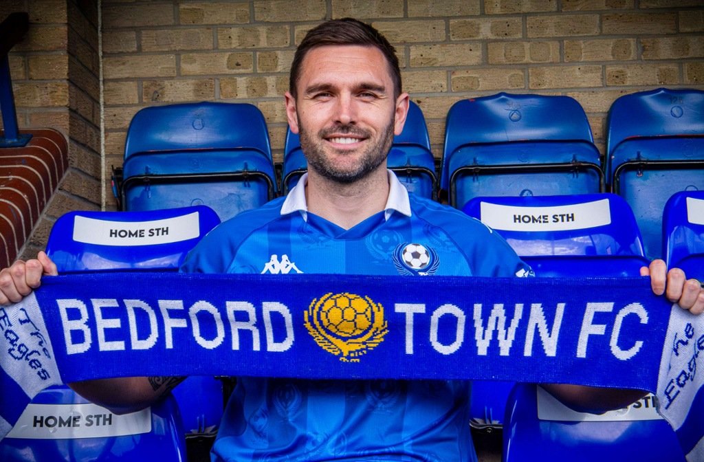 Bedford Town fan favourite, Greg Taylor holding a Bedford Town scarf on the announcement of a new contract in June 2026