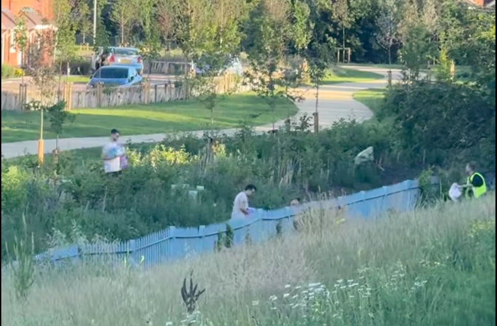 People from Wixams, throwing water and food over the train line safety fence to train staff for people stuck on trains on other lines. Image: Jack Whittle Facebook.