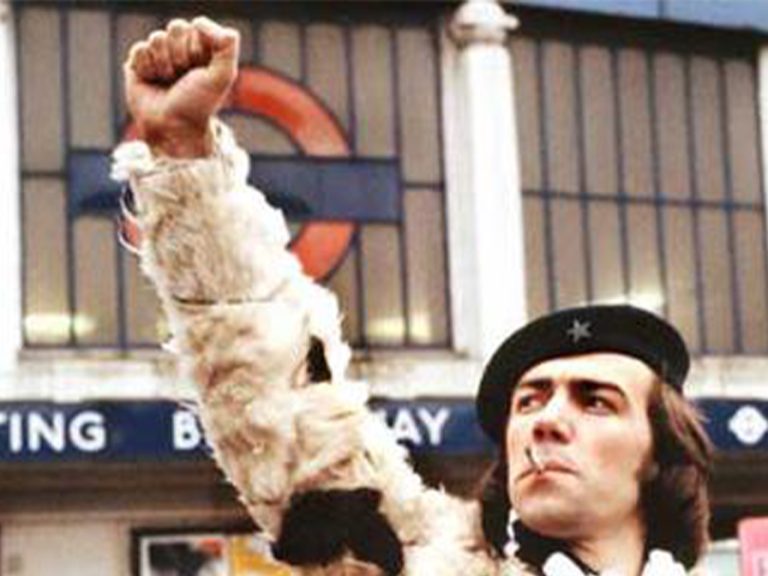 Robert Lindsay as 'Wolfie' Smith in the TV Show Citizen Smith. Wolfie is in front of Tooting Underground Station holding his fist in the air in a revolutionary stance, he has a 'Che Guevara' beret on and a cigarette in his mouth. Image: BBC/Fair Use