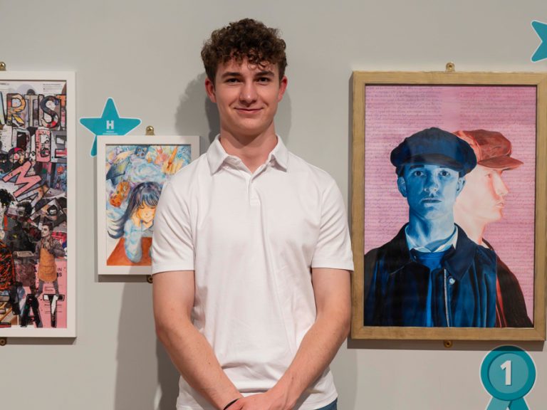 Sam, the winner of category 5 at the Harpur Trust art competition standing in front of his portrait. Image Harpur Trust