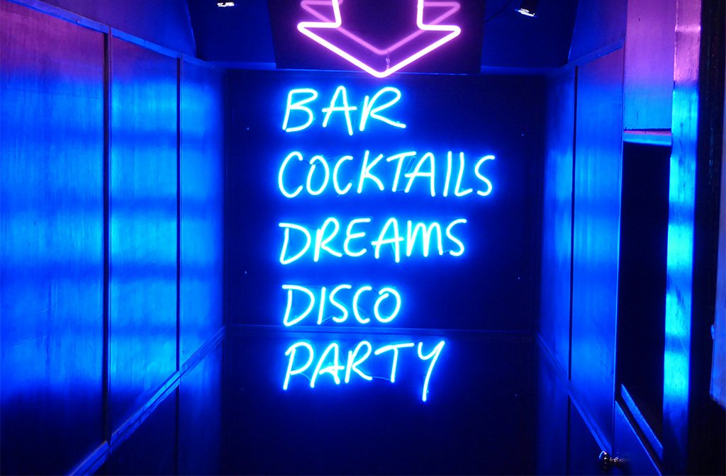 A neon sign at a nighclub entrance which say bar, cocktails, dreams, disco, party Image Nick Fewings unsplash