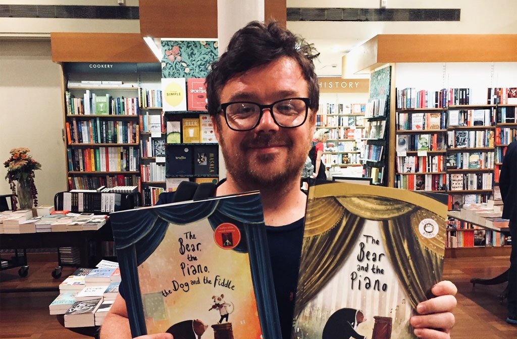 David Litchfield holding copies of his award-winning picture books The Bear and the Piano and the Bear and the Piano and the Dog and Fiddle
