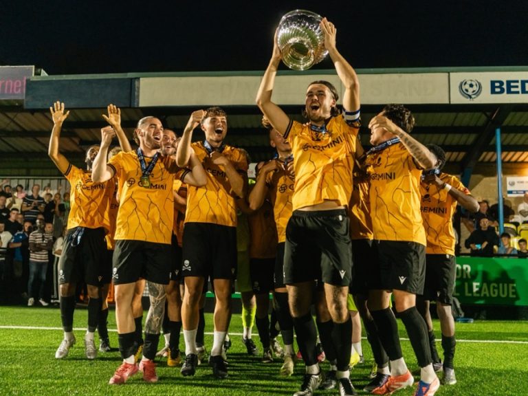 Real Bedford captain, Drew Richardson lifts the Bedfordshire Senior Cup for Real Bedford surrounded by teammates at The Eyrie