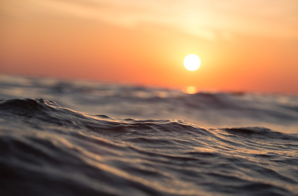 An image of the sunsetting over a choppy sea.
