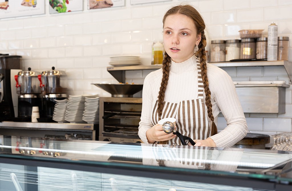 Teenage girl working behind the counter part-time in an ice cream parlour. Image: BearFotos /Shutterstock.