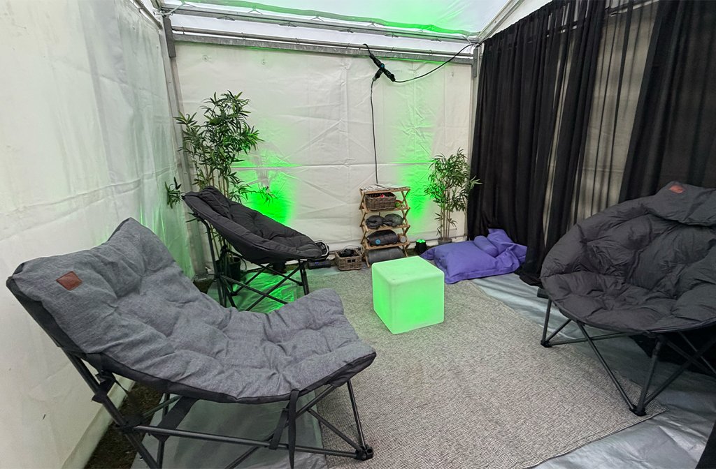 The inside of the SensoryCalm space from EventWell at Bedford Summer Sessions offers a quiet and calm environment for people to regulate and reset. It has comfortable chairs, muted colourful lights, magazines, cushions and plants. Image: Bedford Independent.