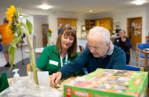 Carers in Bedfordshire volunteer helping an older man with a jigsaw puzzle. Image Carers in Bedfordshire