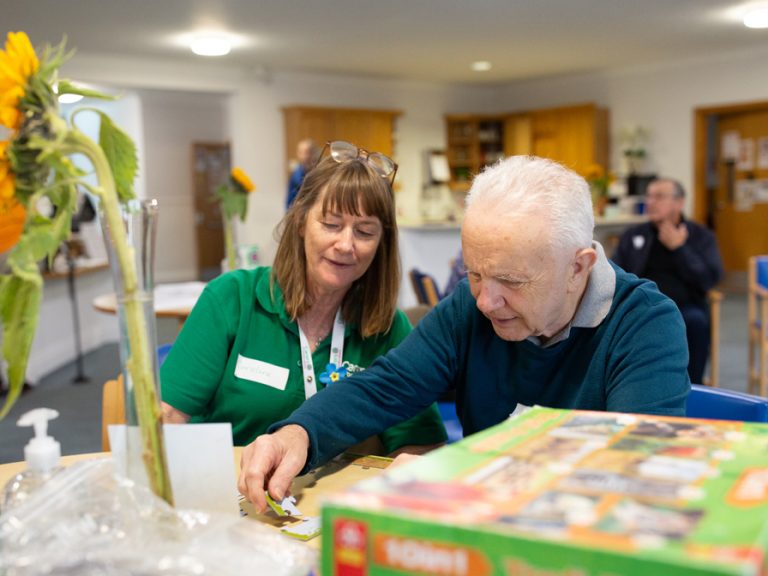 Carers in Bedfordshire volunteer helping an older man with a jigsaw puzzle. Image Carers in Bedfordshire