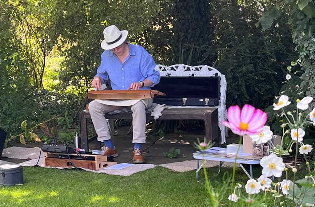 Dan Evans playing a dulcimer in Kathy Brown's Garden in Stevington