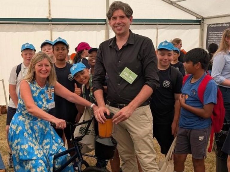 HM Lord-Lieutenant of Bedfordshire, Susan Lousada enjoying a ride on the pedal-powered smoothie bike as schoolchildren attending the event look on. Image: BAEF