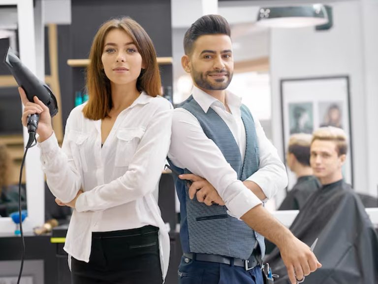 Two haristylists standind posing in a modern spaceous beauty salon. Image Magnific.com