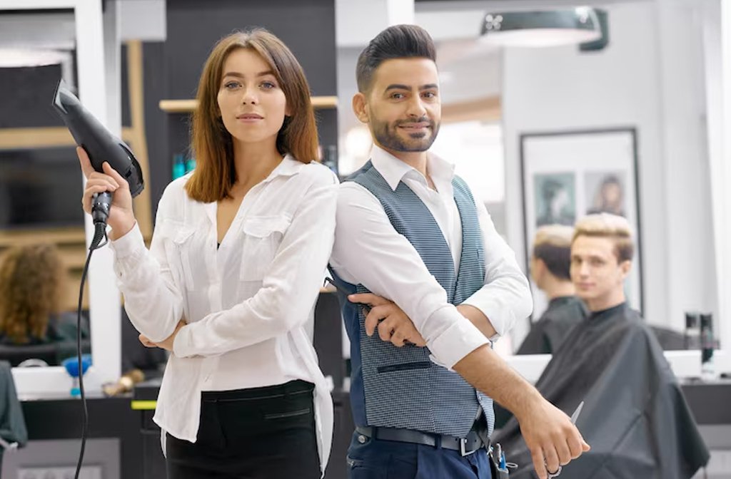Two haristylists standind posing in a modern spaceous beauty salon. Image Magnific.com