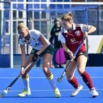 Two hockey players battle for the ball on the blue-clad surface of Chester Road